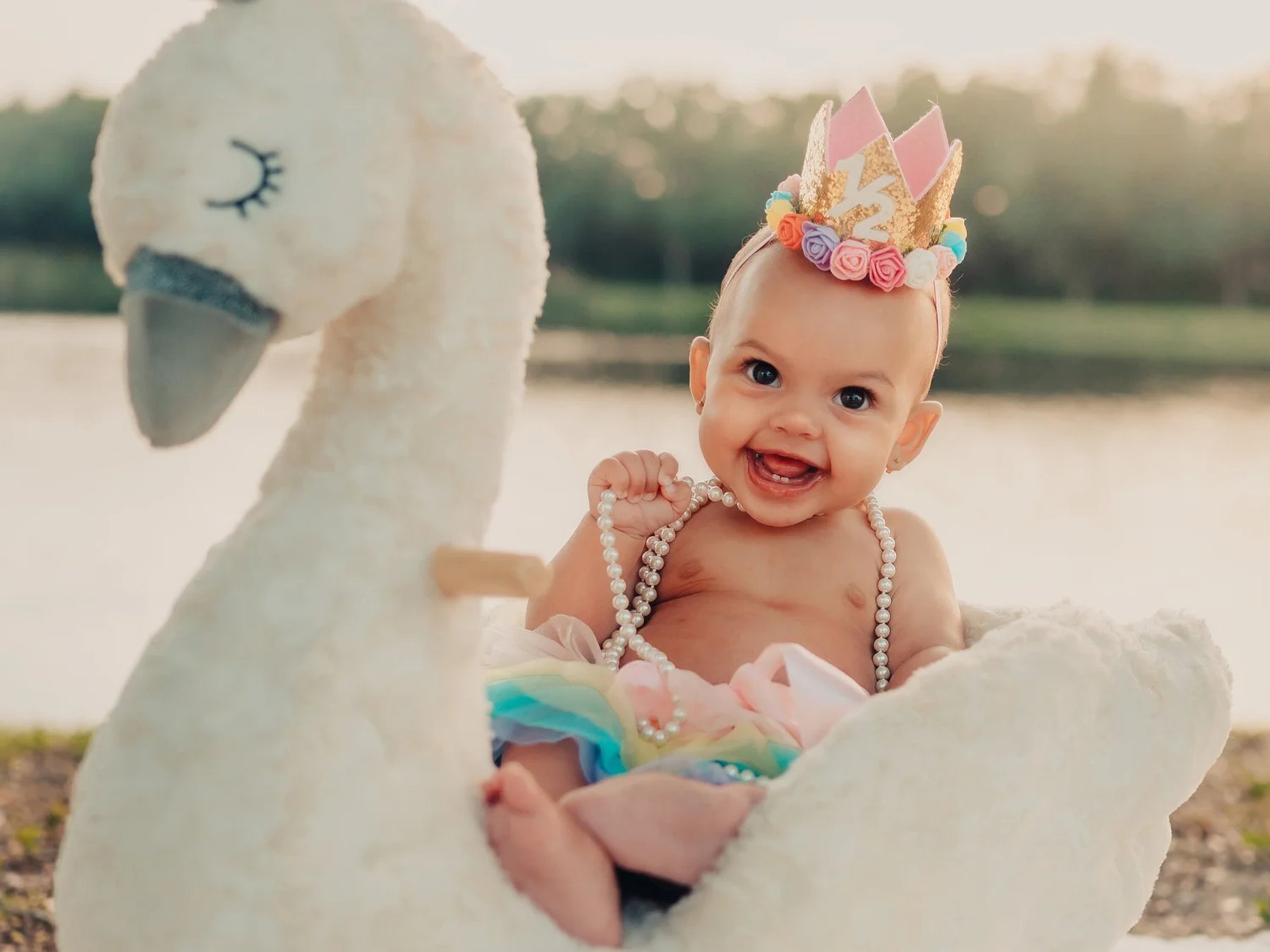 A baby smiling beside a plush swan