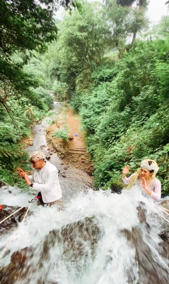 Pernikahan unik ini viral di media sosial setelah sepasang pengantin memanjat air terjun sambil mengenakan busana adat