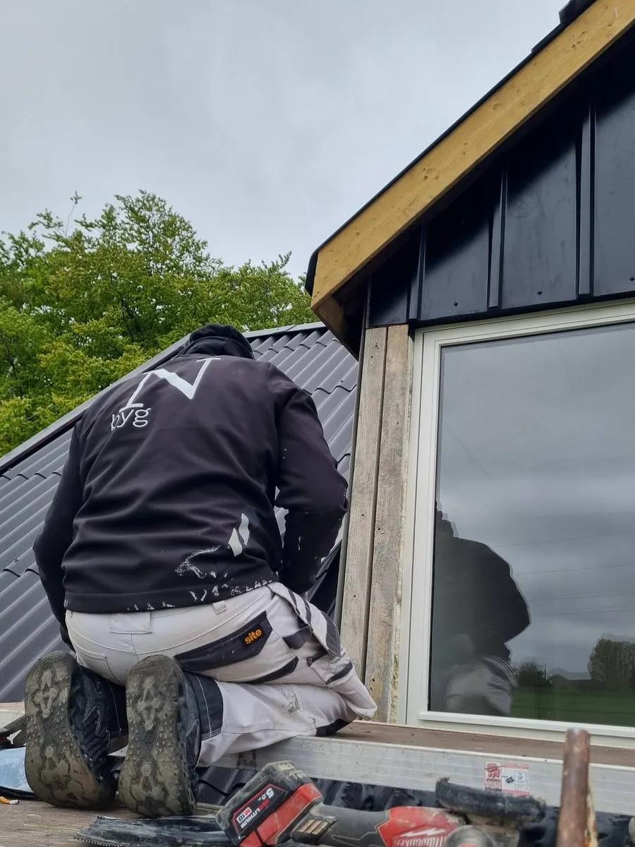 N-byg tagdækker arbejder på tag med bølgeplader ved facadevindue