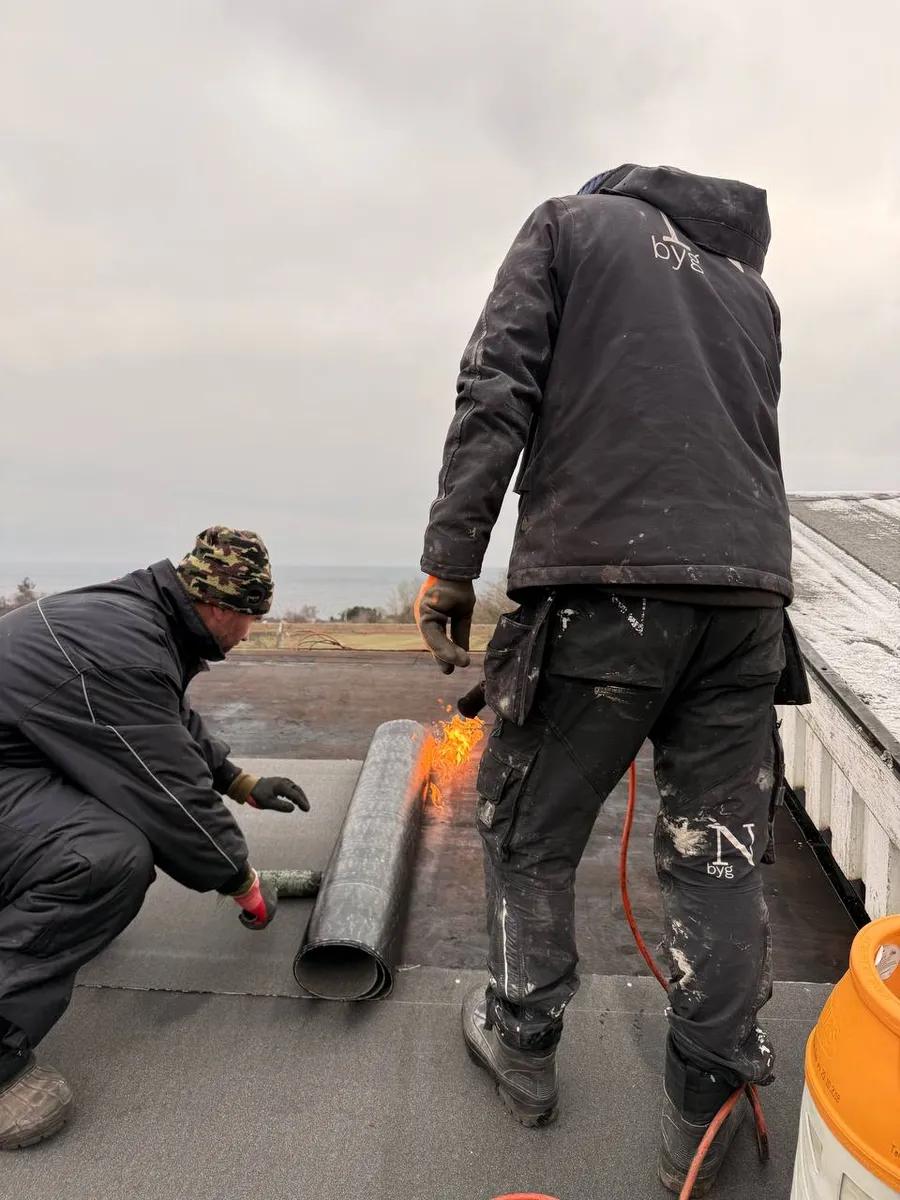 Tagdækkere varmlægger tagpap med gasbrænder på fladt tag