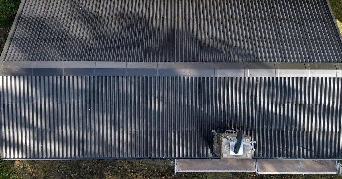 Luftfoto af tagplader i metal på et hus med skorsten og rør