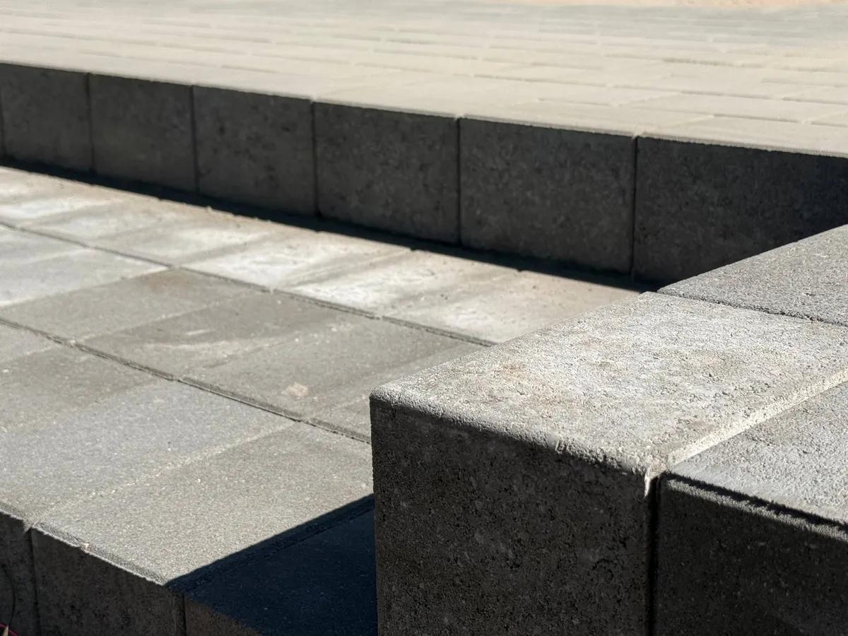 Nærbillede af betonfliser og kantsten i grå beton på terrasse i solskin
