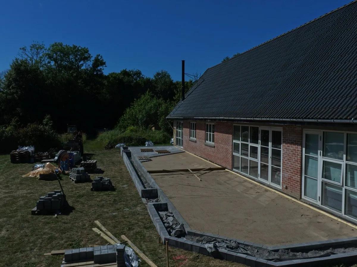 Lægning af betonfliser med ensartede fuger og korrekt fald fra huset: professionel opbygning af fliseterrasse der holder i 30–50 år