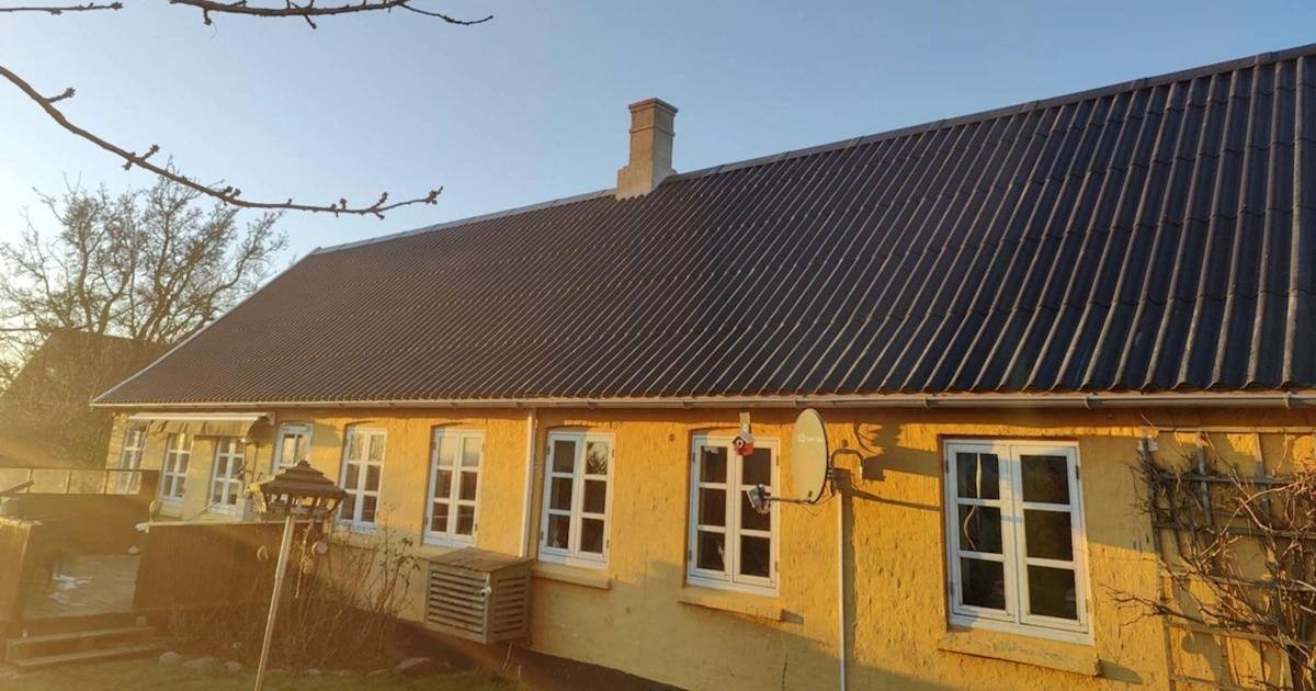 Længehus med nyt tag i mørke bølgeplader og hvide sprossevinduer