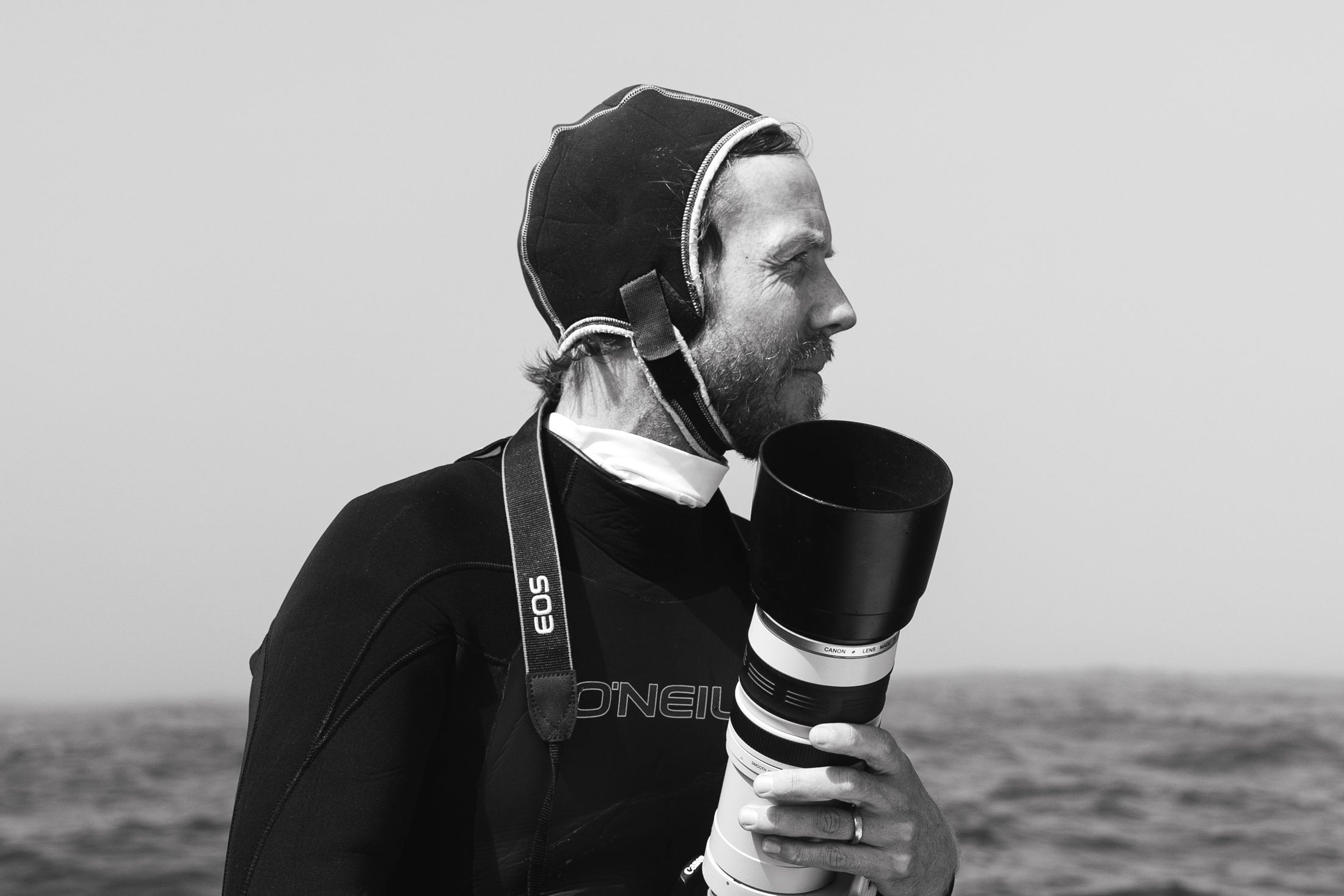 Man in wetsuit holding camera on a boat