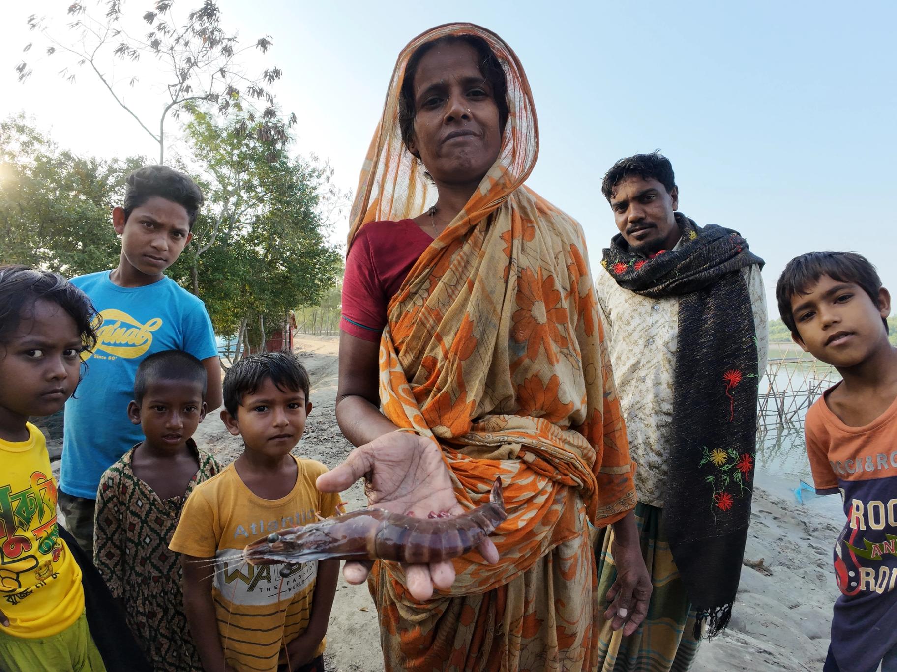 A woman proudly displays a large shrimp