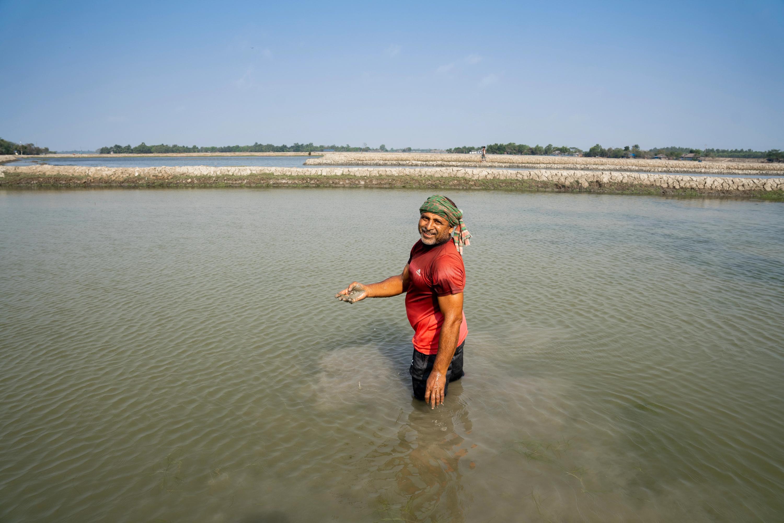 Portrait of a man knee-deep in an aquaculture pond.