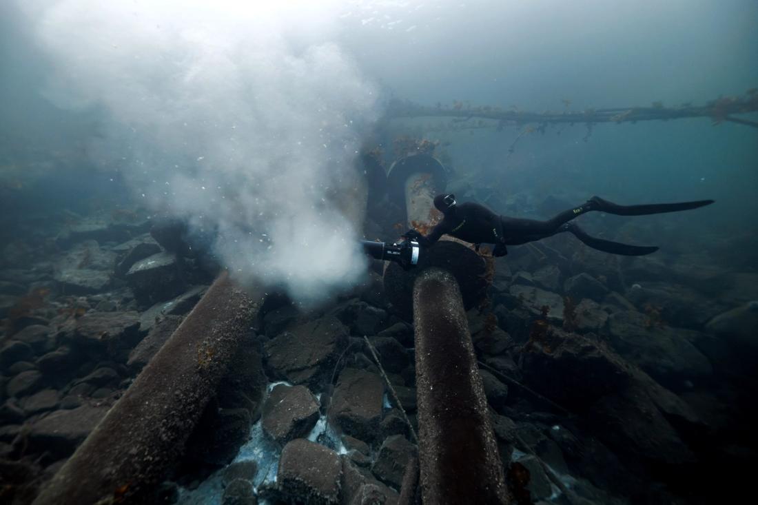 Diver over pipe next to fish farm