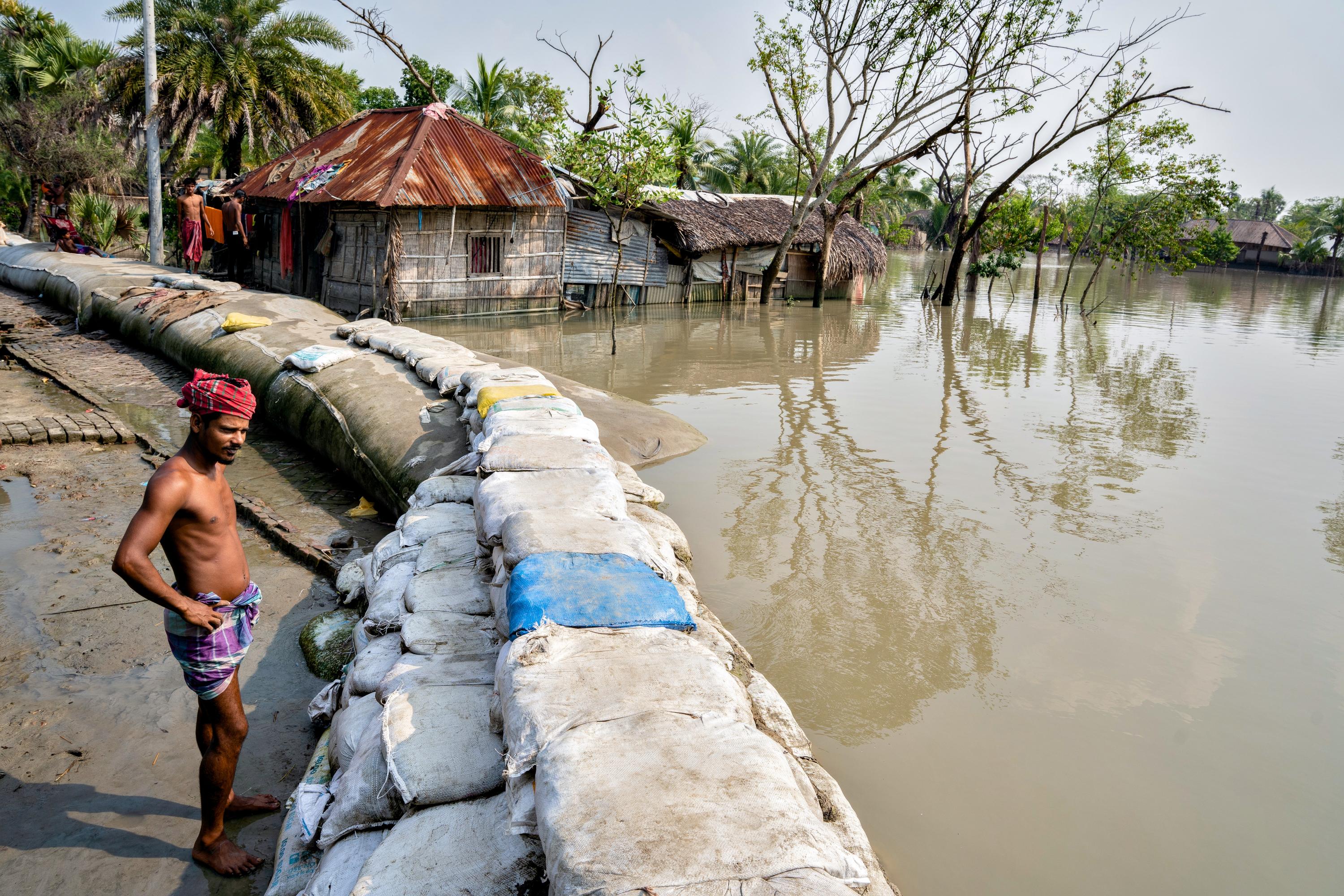 A man stands by sandbags piled up to block out the high tide