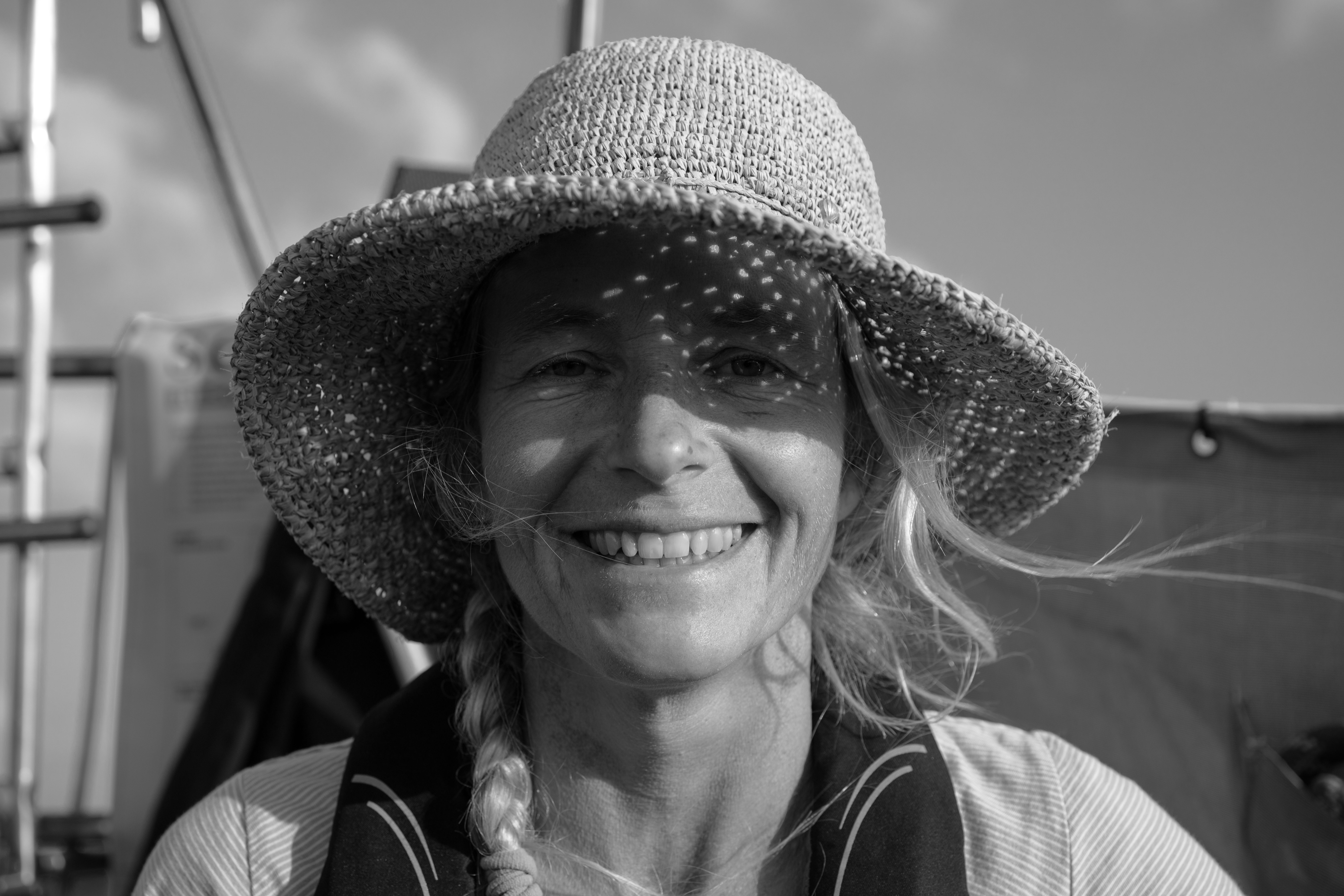 black and white headshot of Lou wearing a hat and smiling