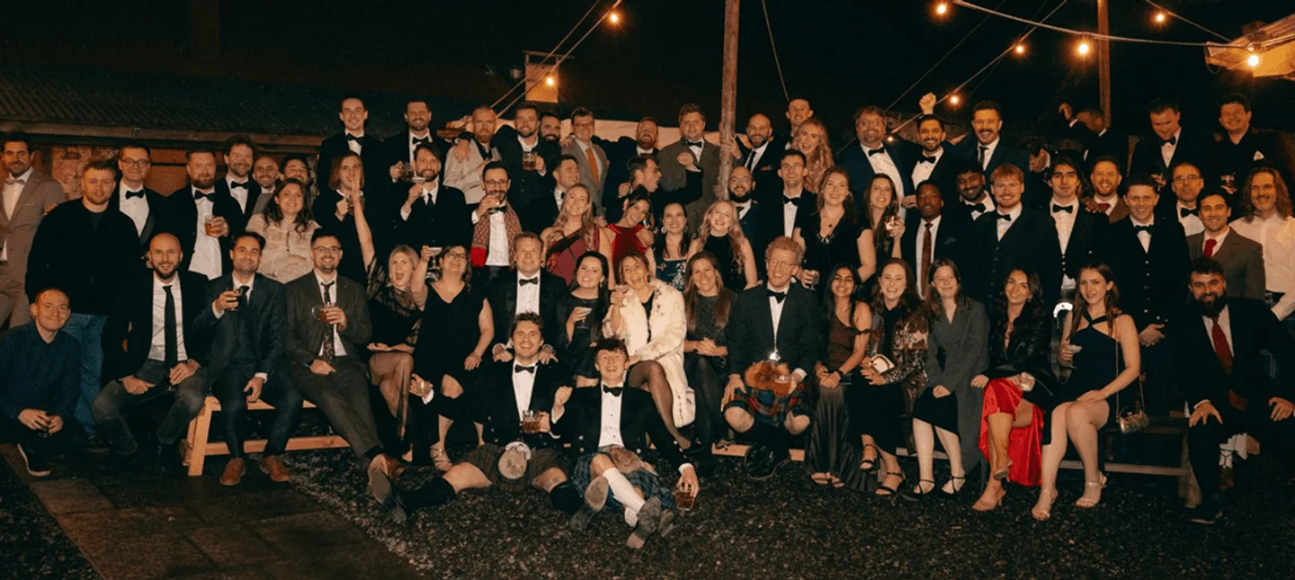 Wordsmith team at an evening celebration, together outdoors under warm string lights.