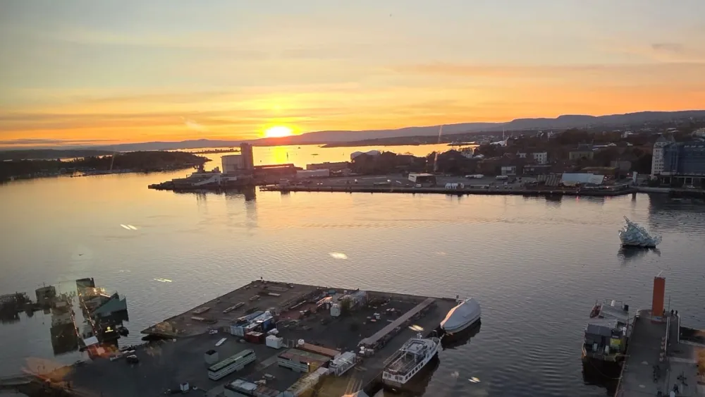 A panoramic sunset view from MUNCH in Oslo, showing the golden light reflecting across the Oslofjord and the city’s waterfront. The Oslo Opera House and surrounding harbor are visible below, capturing the calm beauty of the capital at dusk.