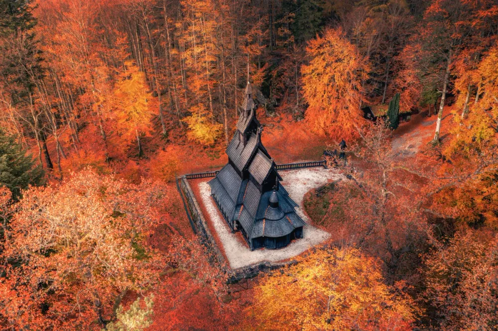 Fantoft Stave Church, surrounded by vibrant autumn colors – a striking blend of history and dramatic landscape. Photo: Karol Bartnik / Visit Bergen