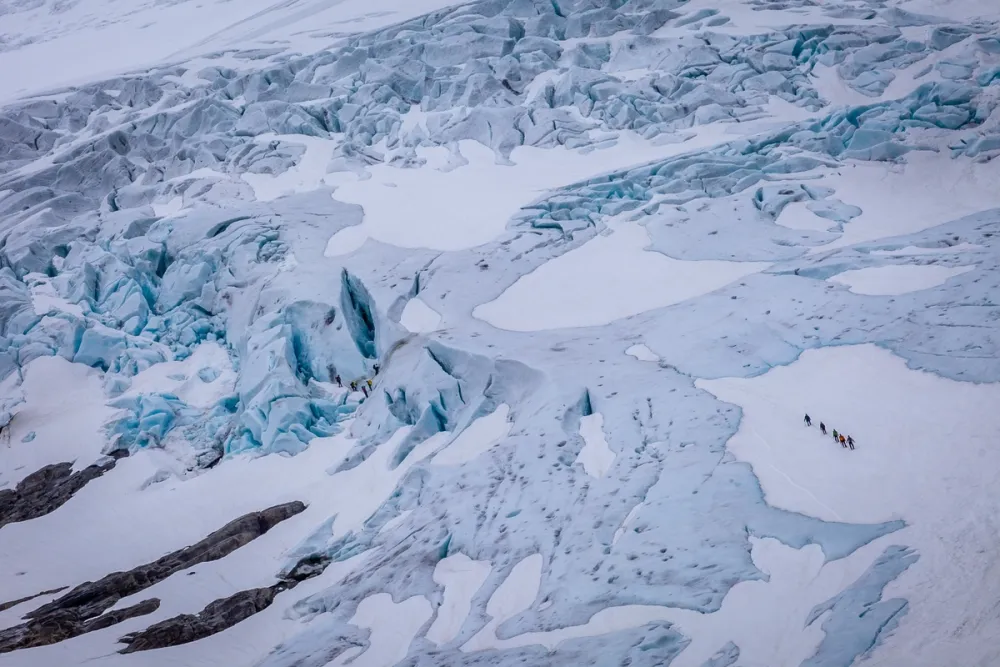 Briksdalsbreen Glacier in Jostedalsbreen National Park, Norway, showing crevasses and blue ice with a group of people walking across the glacier.