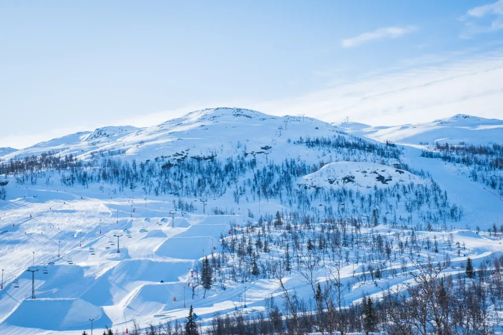Myrkdalen Ski Resort near Voss, Norway, showing snow-covered slopes, ski lifts, and surrounding mountain landscape under a cloudy sky.