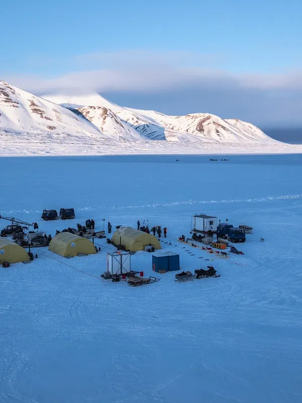 A PolarX production base camp set up on a frozen fjord in Svalbard, Norway. Surrounded by majestic Arctic mountains and pristine snow, the site supports large-scale film shoots in remote polar landscapes, offering dramatic backdrops and 24/7 winter light.