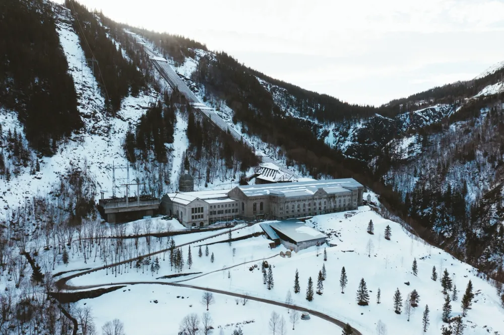 Aerial winter view of Vemork power station surrounded by steep, snow-covered mountains.
