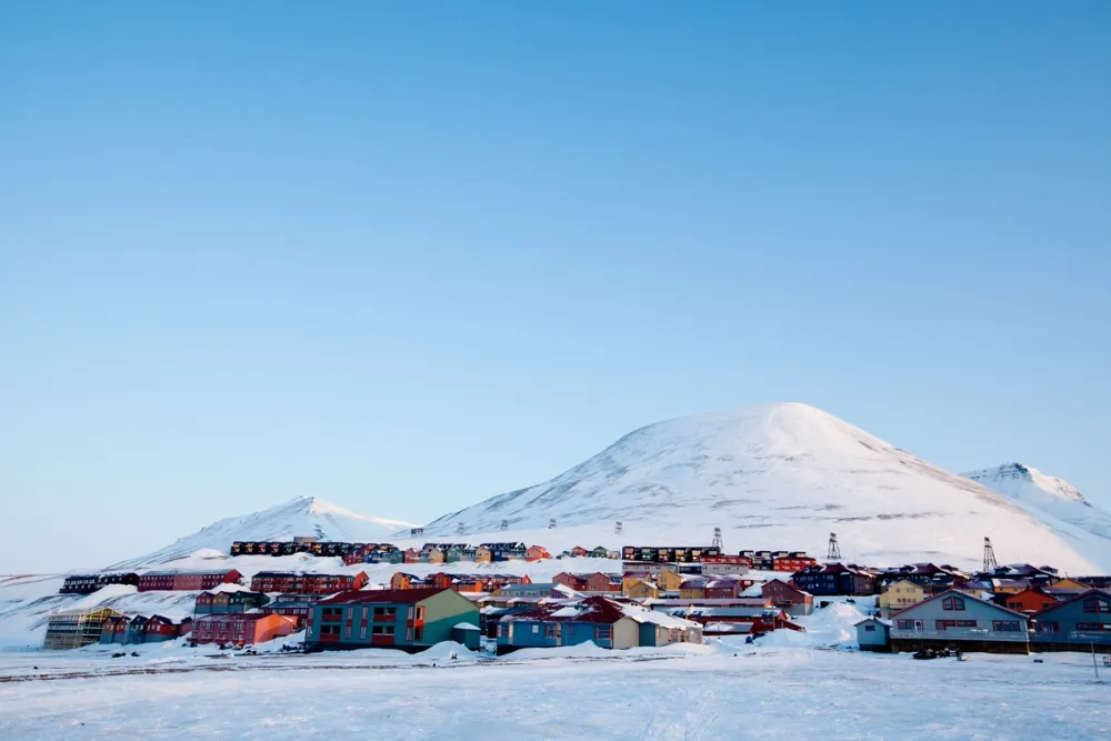 Twilight over Longyearbyen, Svalbard — an Arctic town glowing under winter skies. The colorful buildings, snow-covered streets, and distant mountains showcase the unique infrastructure and atmospheric beauty that make Svalbard an ideal filming location in the High North.