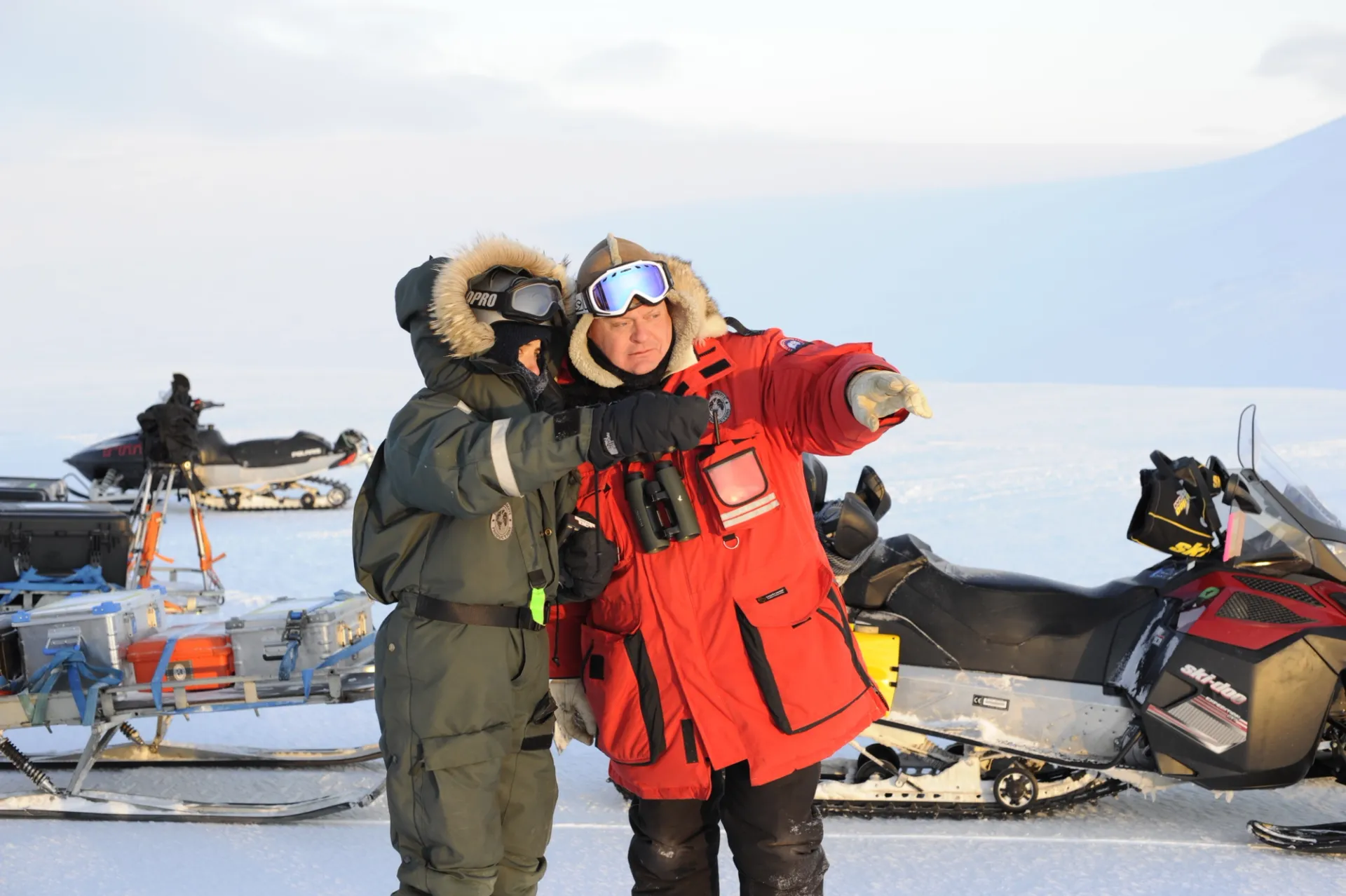 Jason Roberts, founder of PolarX, coordinates with crew on location in the Arctic. Equipped with snowmobiles and sleds, the team exemplifies professional Arctic expedition logistics, critical for major film and documentary productions in extreme conditions.