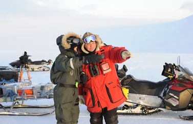 Jason Roberts, founder of PolarX, coordinates with crew on location in the Arctic. Equipped with snowmobiles and sleds, the team exemplifies professional Arctic expedition logistics, critical for major film and documentary productions in extreme conditions.