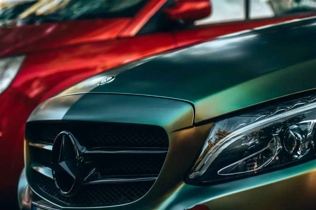 Close up moncong mobil berwarna hijau keemasan chameleon di samping mobil merah mengkilap
