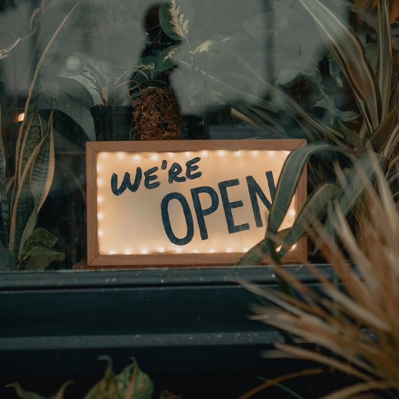"We're Open" sign in window of storefront