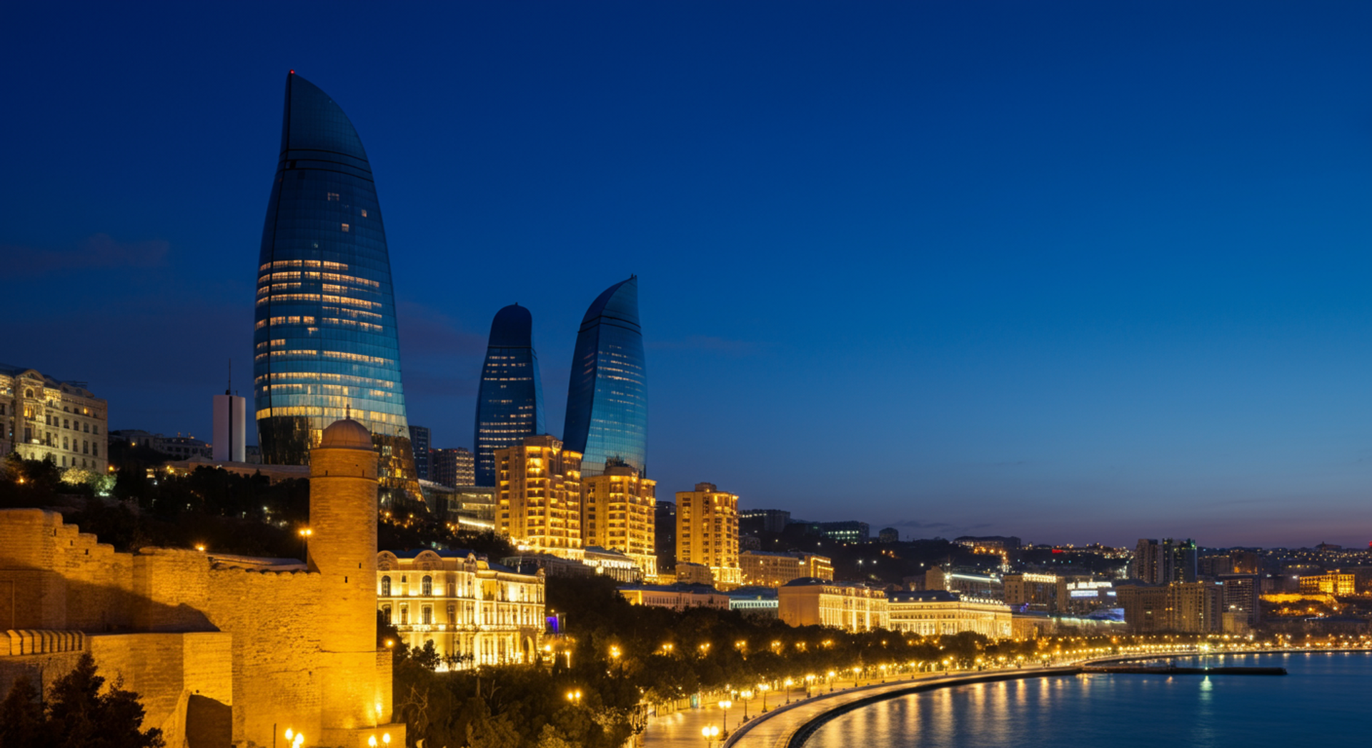 The Flame Towers rising above the Baku skyline at dusk, with the ancient Old City walls and Maiden Tower in the foreground