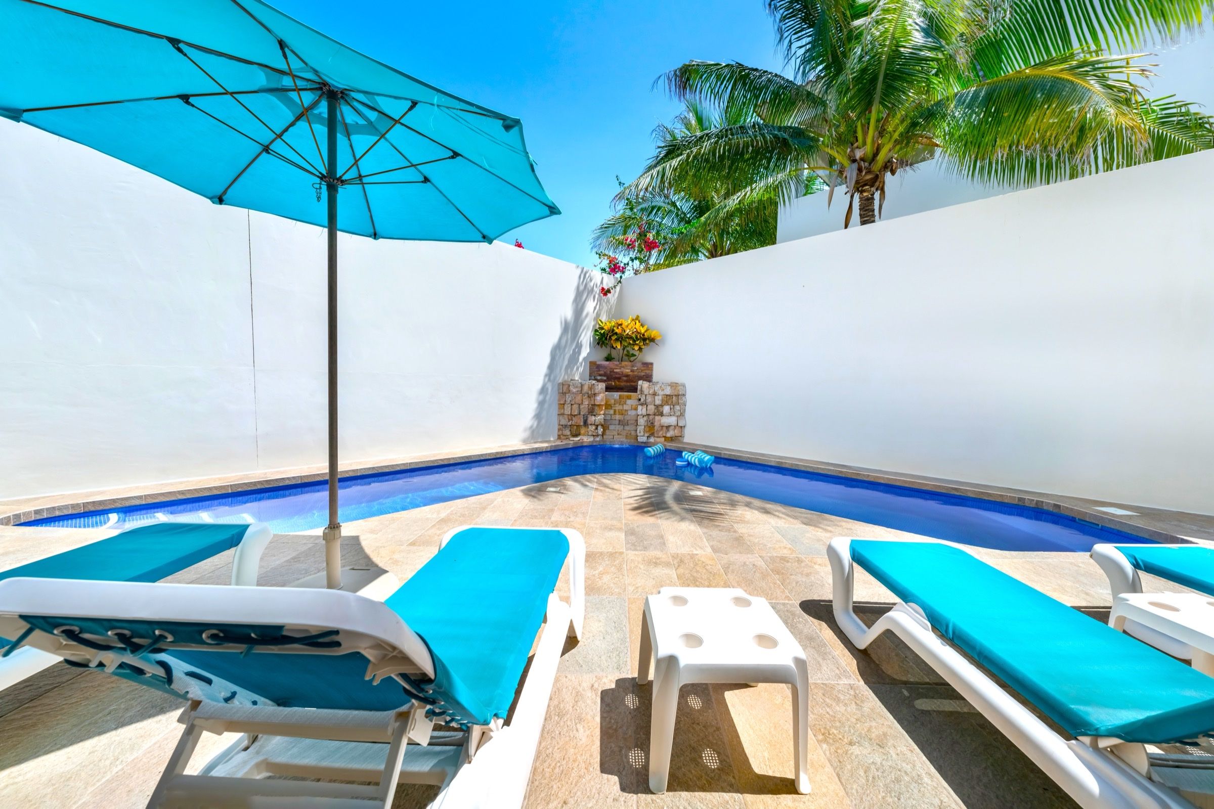 Private pool with turquoise umbrella and lounge chairs