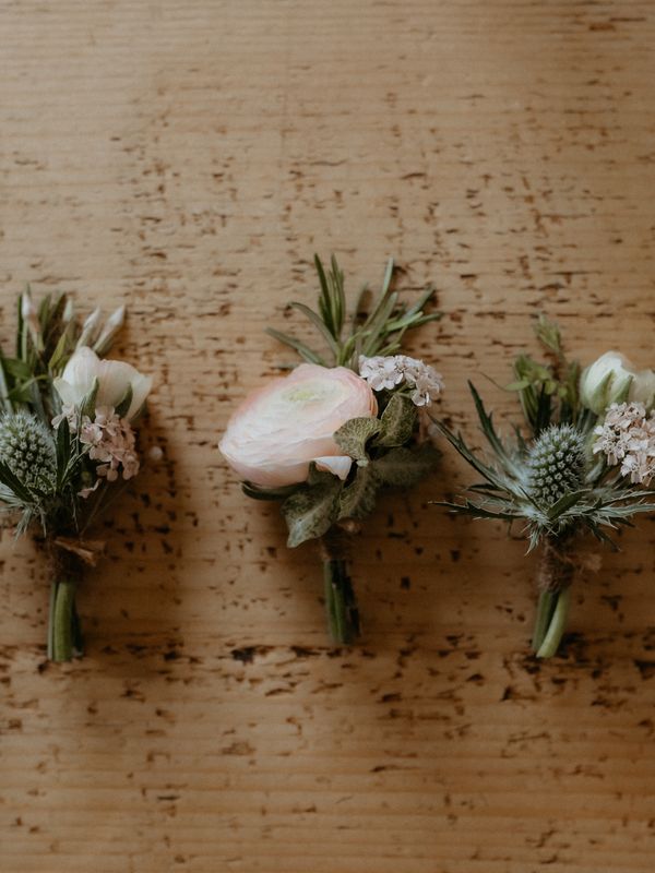 A selection of buttonholes, some with a thistle, some with ranunculus, for May wedding