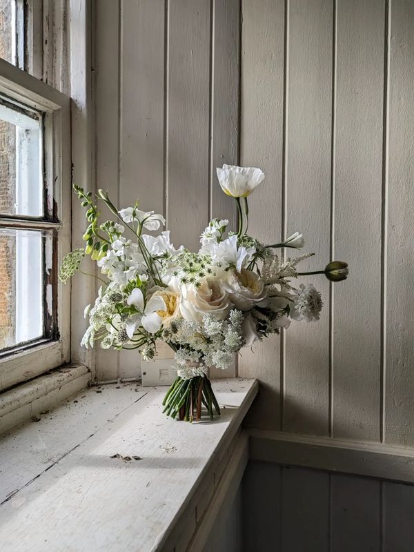 White bridal bouquet sits on a window sill for the picture
