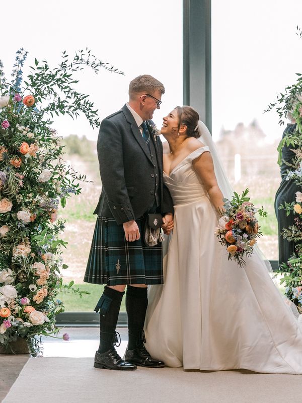 Bride and groom are just married in front of their flower arch