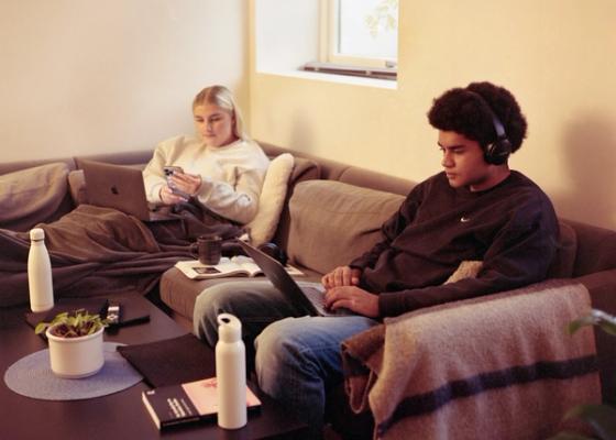 To studenter i eget kollektiv som jobber på pc fra sofaen