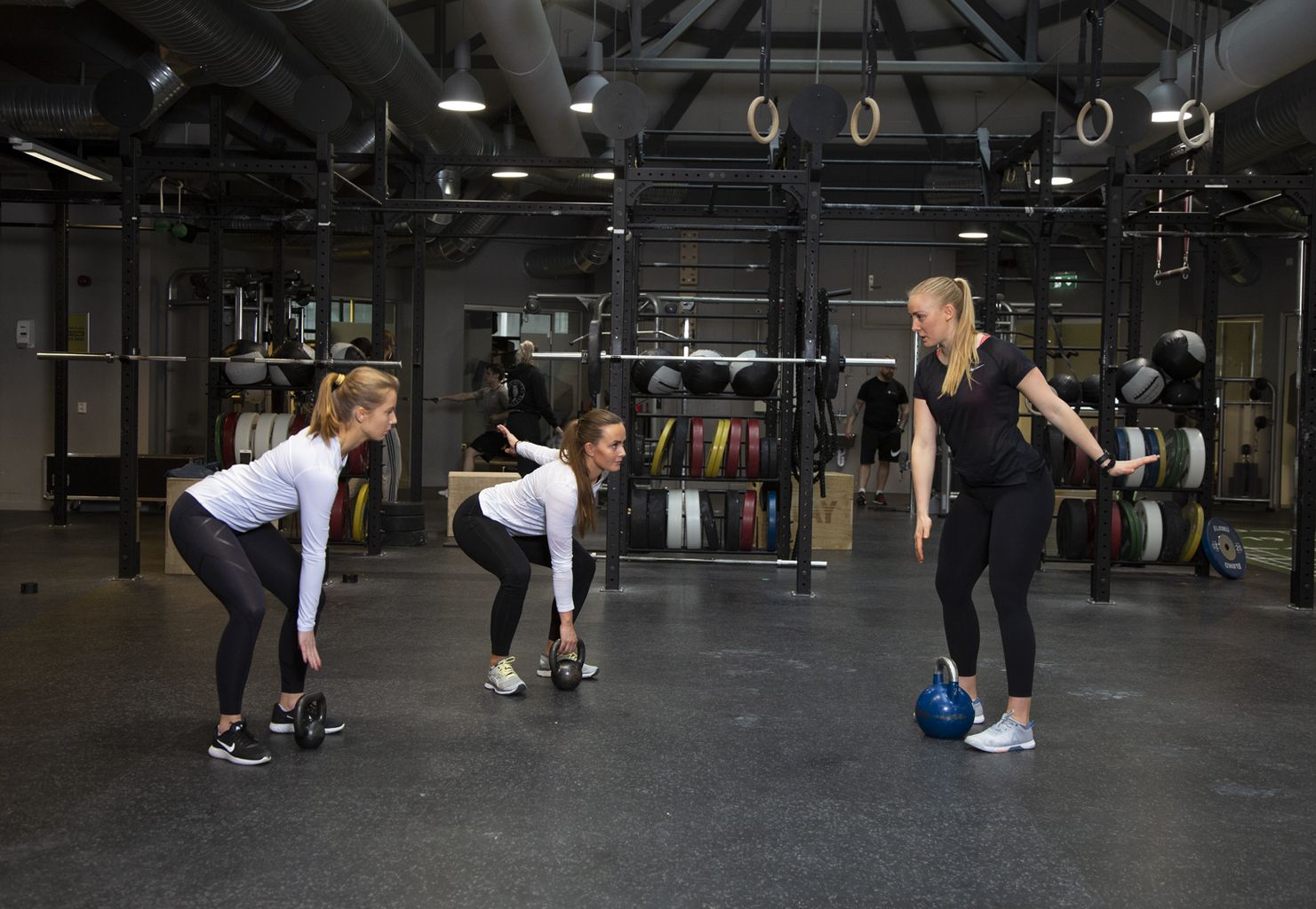Three women working out together with kettlebells.