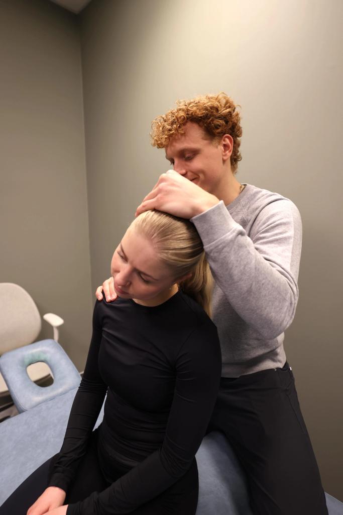 fysioterapaut som hjelper en jente med nakken