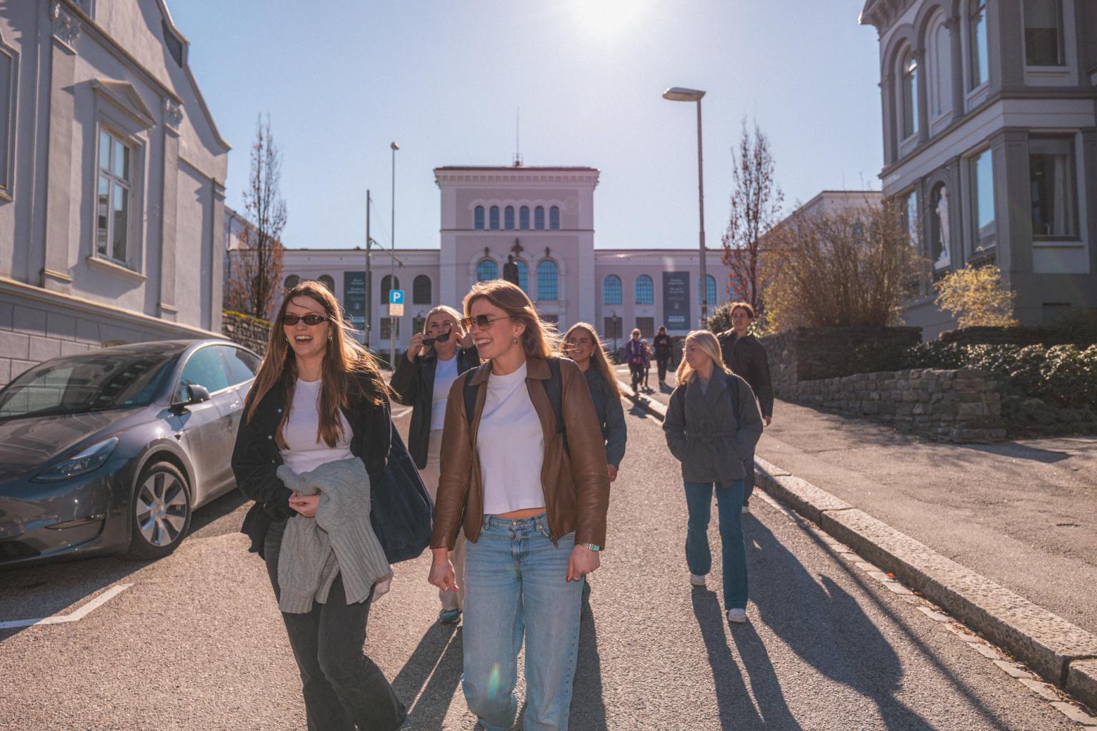 To kvinner som går ned en bakke, med flere følgende etter