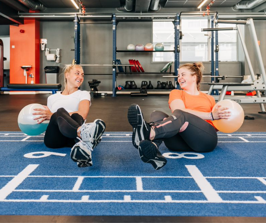 Two women exercising with a ball.
