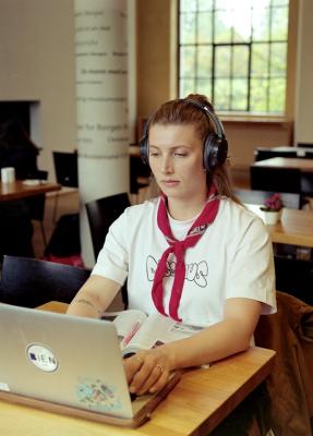 Konsentrert kvinne med hodetelefoner som skriver på en laptop.