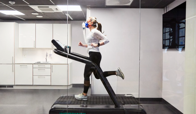 A woman running on a treadmill in a room, focused and determined to achieve her fitness goals.