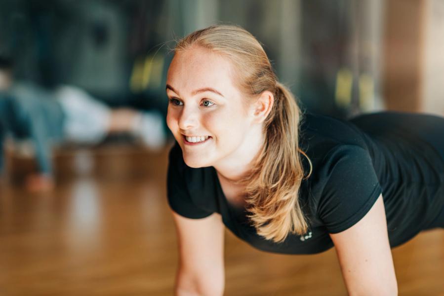 A woman joyfully doing push-ups with a smile on her face.