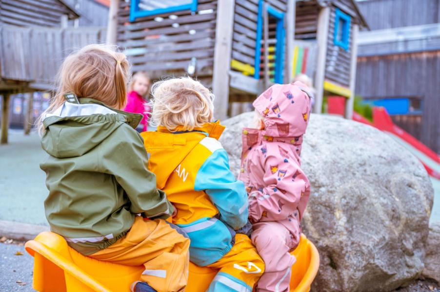 Children in colorful rain gear at the playground.