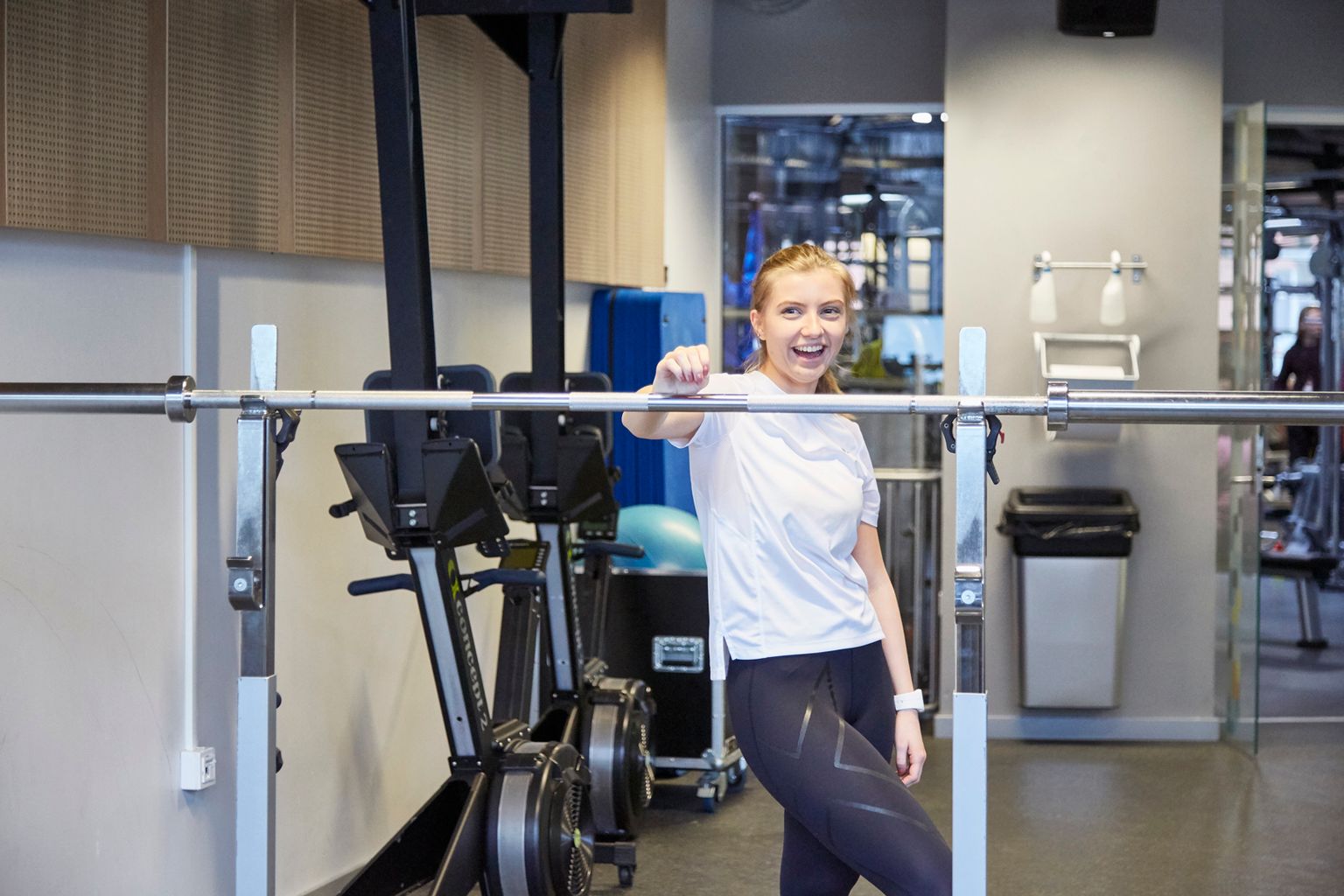  Smiling woman holds barbell during workout.