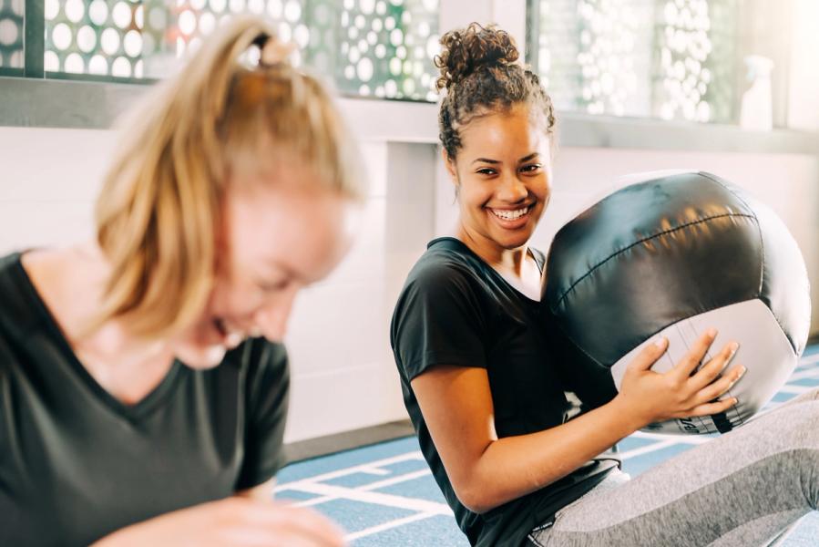 To kvinnelige studenter trener med ett smil om munnen.