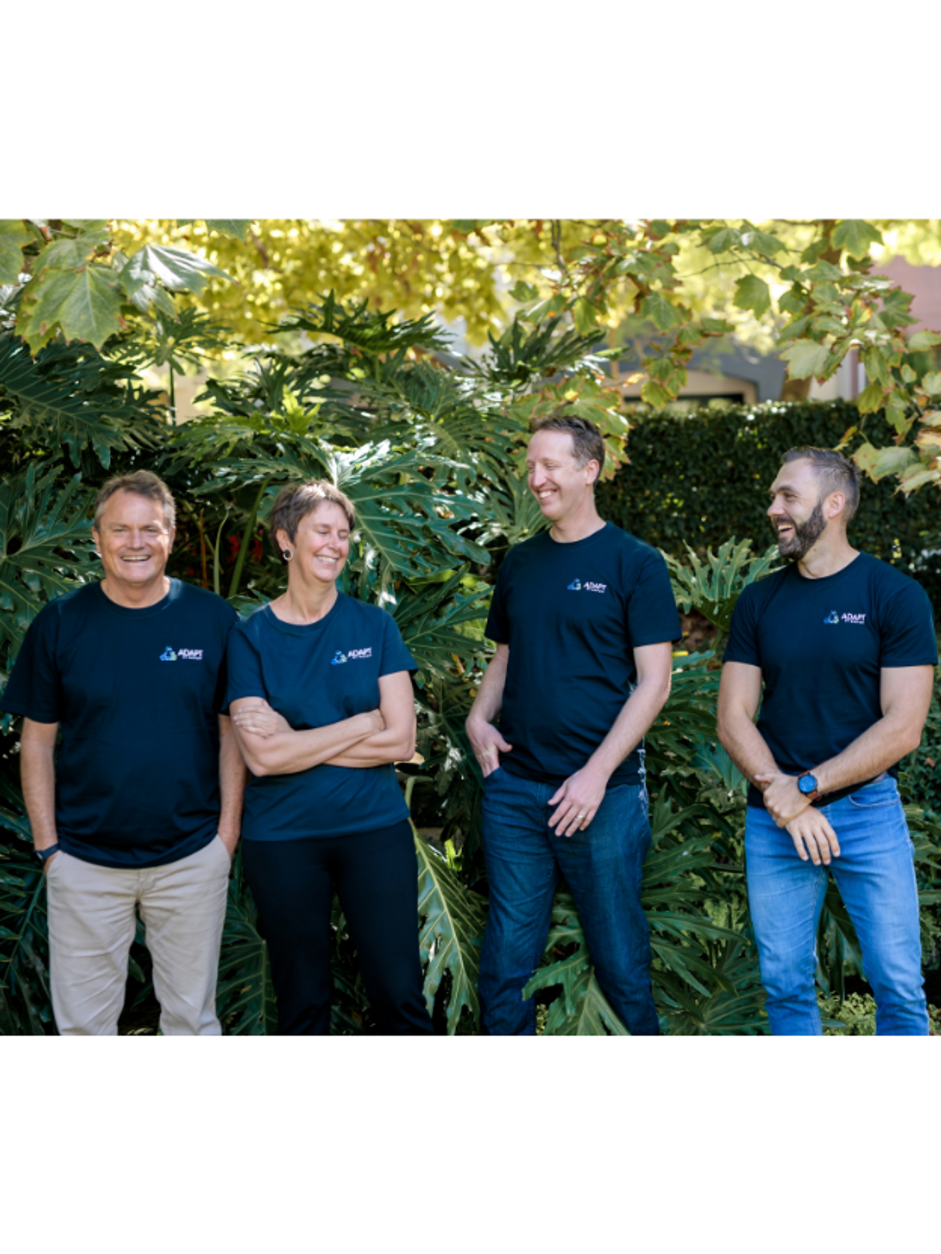 Four members of the Adapt team standing in a garden, wearing Adapt T-shirts, and smiling.
