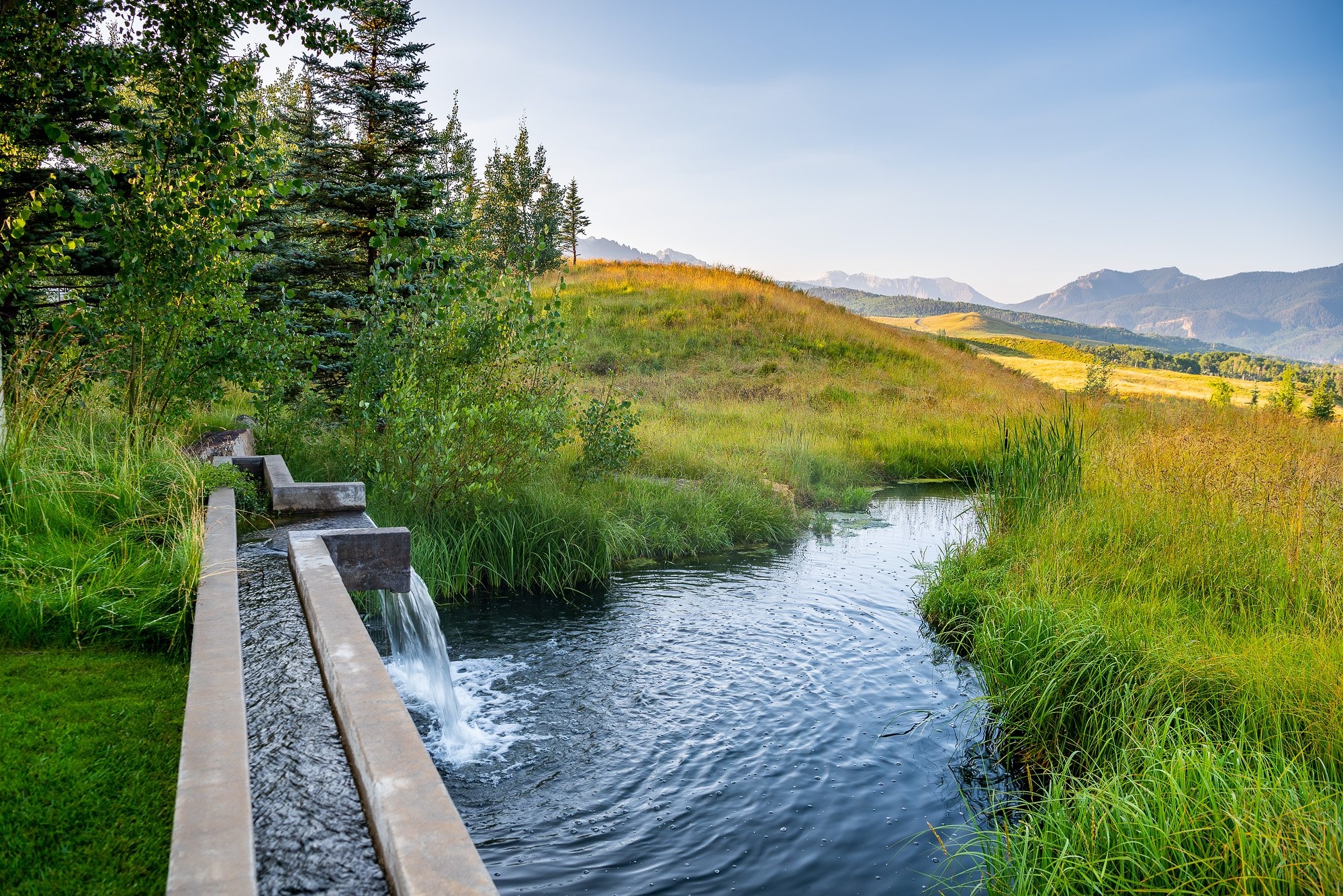 A concrete waterfall overlooking rolling hills and mountains