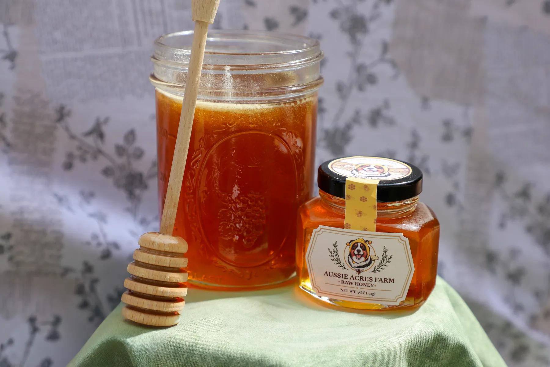 A jar of raw honey with a wooden honey dipper