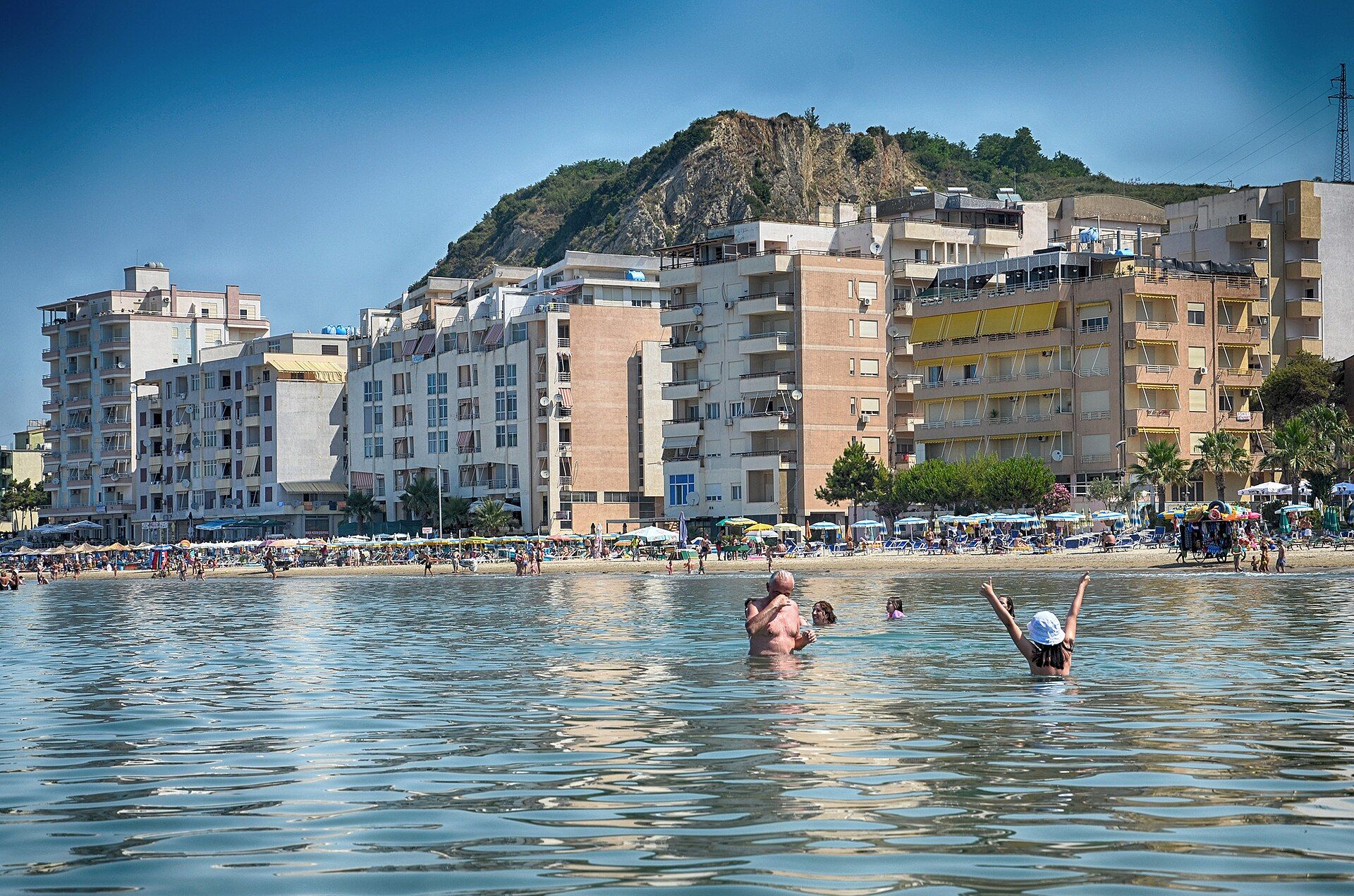 Bathers at Shkëmbi i Kavajës beach below the rock