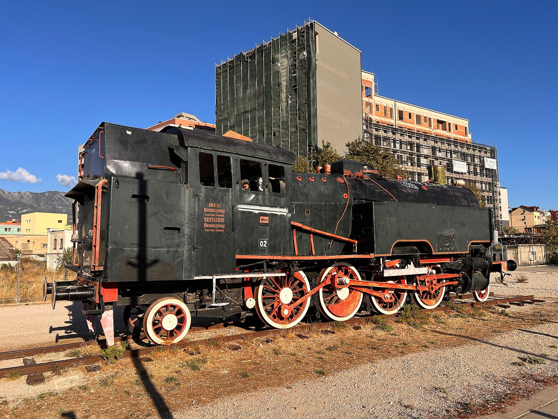 The restored steam locomotive on Bulevardi i Ri, Tirana, with new towers behind — Bdx