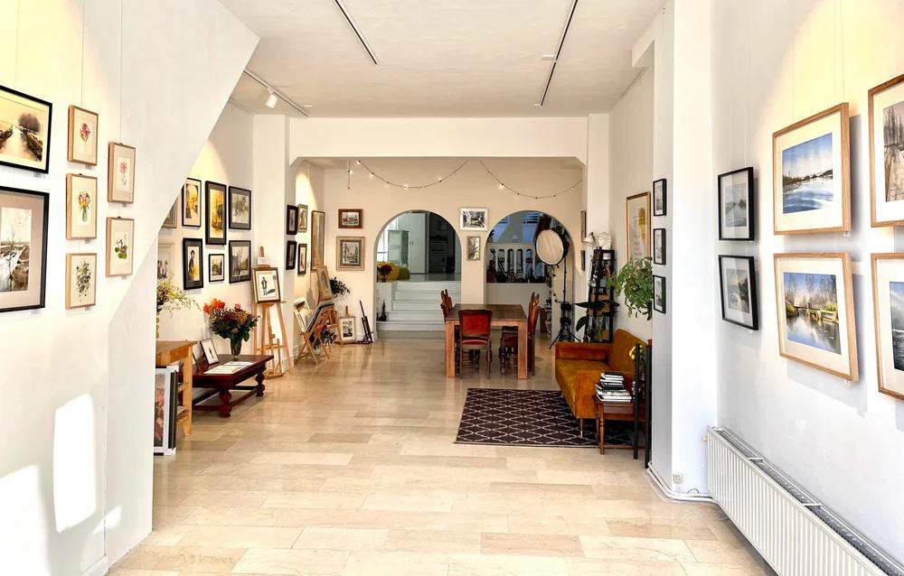 Bright gallery space with tables and canal view at NEST Aquarel Atelier Amsterdam