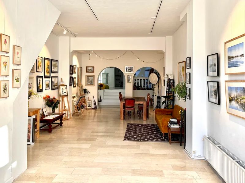 Bright gallery space with tables and canal view at NEST Aquarel Atelier Amsterdam