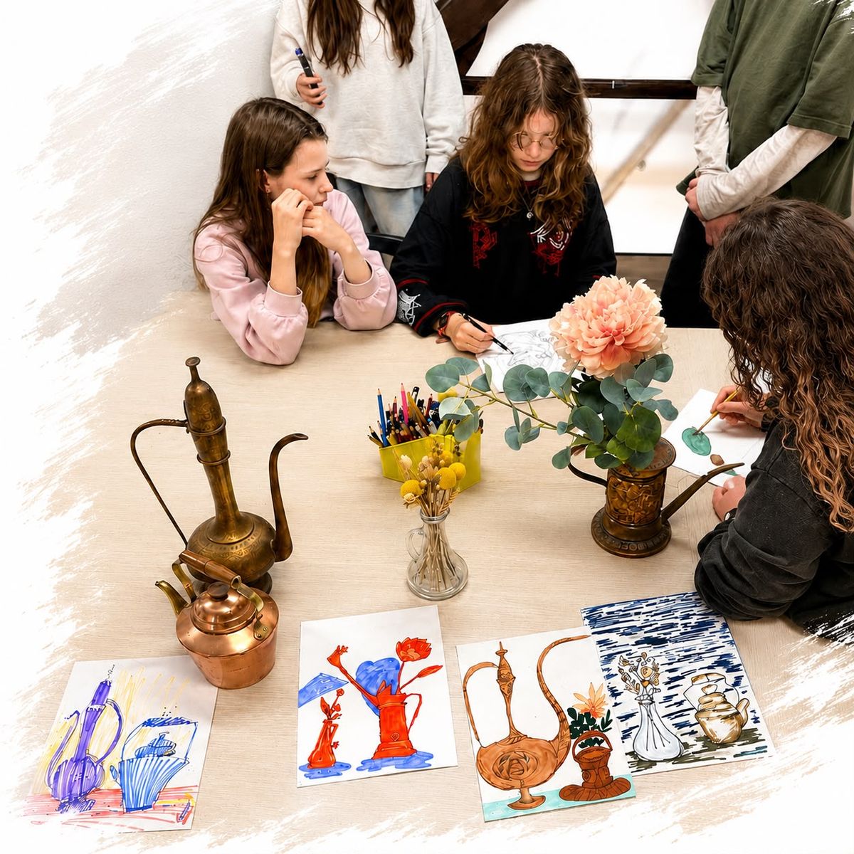 Three students at a table making ink and watercolour sketches of ornate copper jugs, with pencils, eucalyptus and a peony in the centre.